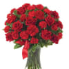 Red roses and carnations in a clear glass vase with a red ribbon
