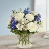 White and blue mixed bouquet in a clear glass vase