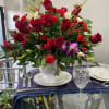 Red rose centerpiece in a clear glass vase on a set table