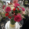 Pink and red rose centerpiece in a glass vase on a set table