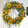 Sunflower wreath with blue flowers on a black stand