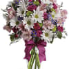 Bouquet of pink and white flowers in a glass vase with a magenta ribbon