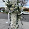 Tall white floral standing spray on an easel with ribbon