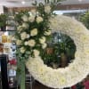 White rose arrangement beside a large white chrysanthemum wreath