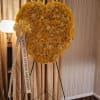 Heart-shaped yellow floral standing spray on an easel with a memorial ribbon