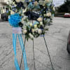 Heart-shaped funeral wreath with white and blue flowers on a stand