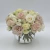 Blush and ivory roses arranged in a clear glass vase