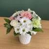 Pink and white flowers arranged in a white vase