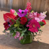 Bright pink and red mixed bouquet in a green glass vase