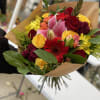 Mixed bouquet of roses, lilies, and daisies wrapped in brown paper