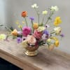 A loose, airy centerpiece of in-season blooms that greets the recipient with