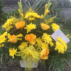 Yellow and orange flowers arranged in a white container with a yellow bow.