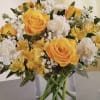 Yellow roses and white flowers arranged in a clear glass vase