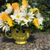 Yellow mug with a smiley face holding white daisies and yellow roses