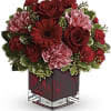 Red and pink flower arrangement in a square glass vase