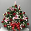 Red roses and pink lilies arranged with baby's breath and a red ribbon