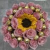 Pink roses and a sunflower arranged with gold-wrapped chocolates