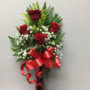 Red roses arranged in a tall vase with baby's breath and a red ribbon