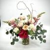 Mixed bouquet of roses, peonies, and snapdragons in a glass vase
