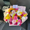 Mixed bouquet of gerbera daisies, sunflowers, and pink roses wrapped in pale pink paper