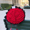 Large bouquet of red roses wrapped in black paper on a bench
