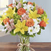 Bouquet of yellow lilies, orange roses, and white daisies in a glass vase