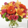 Bright mixed bouquet in a clear glass vase with orange lilies and pink roses