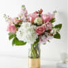 Pink and white bouquet in a clear glass vase with a gold base
