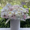 White orchids and blush roses arranged in a tall gray vase