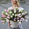 Large bouquet of pink, white, and purple tulips in a white container
