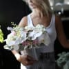 Woman holding a pastel bouquet with white orchids and pink roses