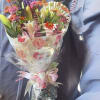 Bouquet of mixed flowers wrapped in floral paper with a pink ribbon