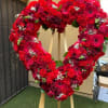 Large heart-shaped wreath of red flowers on a wooden easel