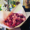 Large hand-tied bouquet of pink and purple roses wrapped in pale pink paper