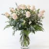 Blush pink roses in a clear glass vase with mixed greenery