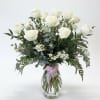 White roses in a clear glass vase with mixed greenery