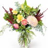 Mixed bouquet of pink and yellow flowers in a clear glass vase