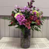 Mixed pink and purple flowers arranged in a glass jar vase