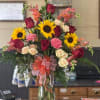 Mixed bouquet of sunflowers, roses, and carnations in a glass vase