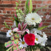 Pink and white mixed flower arrangement in a pink container with a plaid ribbon