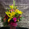 Tall mixed bouquet of yellow lilies and pink flowers in a glass vase