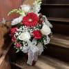 Red and white flower arrangement in a vase with a sheer bow