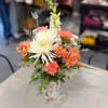 Mixed bouquet of white and coral flowers in a patterned vase