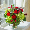 Red roses and green hydrangeas in a clear glass vase