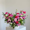 Pink and magenta mixed flower arrangement in a white vase