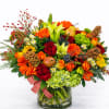 Bright mixed bouquet with roses, lilies, and gerbera daisies in a glass vase