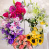 Colorful floral wreath on a black stand with roses, lilies, and sunflowers
