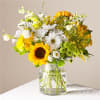 Bouquet of sunflowers, white daisies, and yellow flowers in a glass vase
