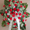 Standing wreath of red carnations with white baby's breath and ribbon