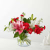 Bouquet of red roses, pink lilies, and white flowers in a clear glass vase